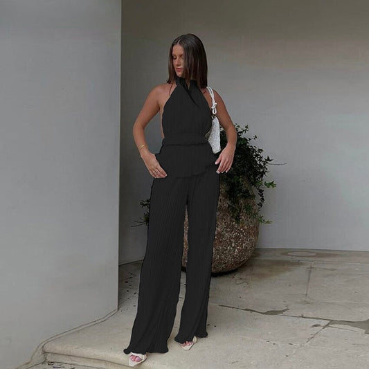 Frau in schwarzem ärmellosen Jumpsuit, elegante Mode, Sommeroutfit, vor modernem Gebäude.