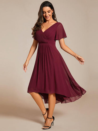 Weinrotes Kleid in Bewegung, Model blickt lächelnd nach unten, dazu schwarze Riemchensandaletten. 47