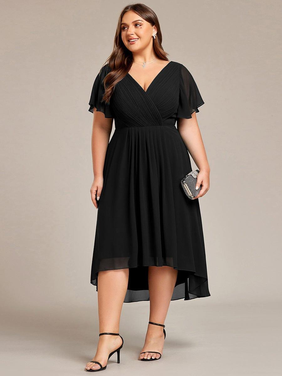Curvy-Model im schwarzen Kleid in Frontansicht mit kleiner glitzernder Clutch, hoch-tiefer Chiffonsaum. 30