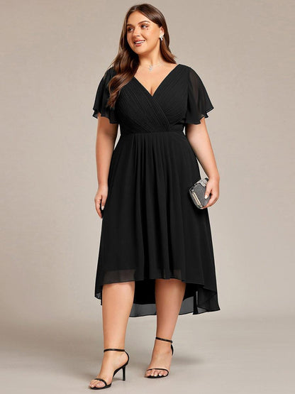 Curvy-Model im schwarzen Kleid in Frontansicht mit kleiner glitzernder Clutch, hoch-tiefer Chiffonsaum. 30