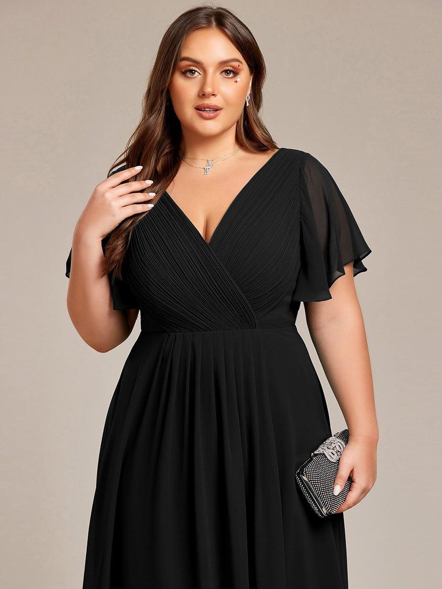 Nahaufnahme des Oberteils am Curvy-Model: schwarzes gerafftes Wickeloberteil, V-Ausschnitt, Flatterärmel, glitzernde Clutch in der Hand. 28