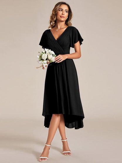 Model im schwarzen Kleid mit kleinem weißen Rosenstrauß in der Hand, leicht seitlich stehend. 24