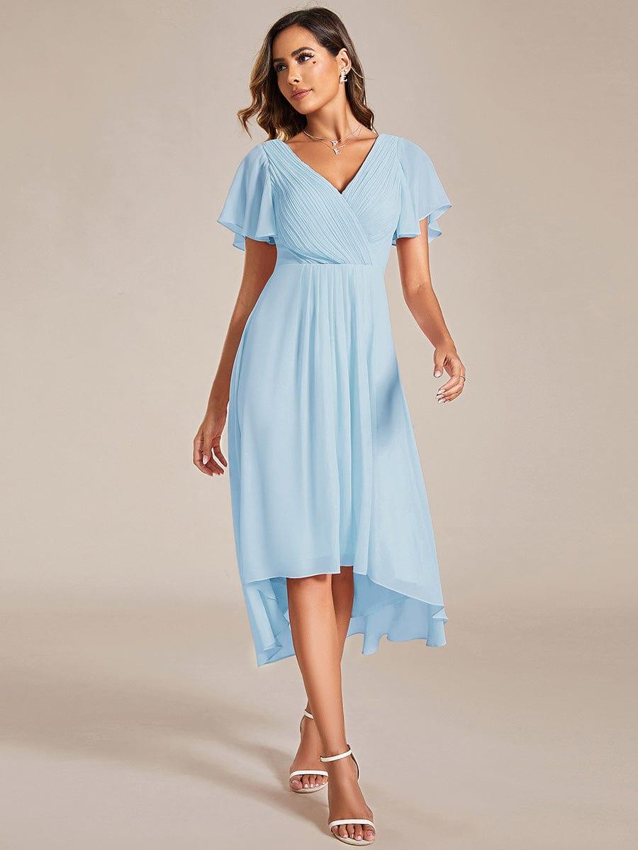 Model in hellblauem Chiffonkleid mit V-Ausschnitt, Flatterärmeln und vorne kürzerem Saum, Frontansicht mit weißen Sandalen. 84