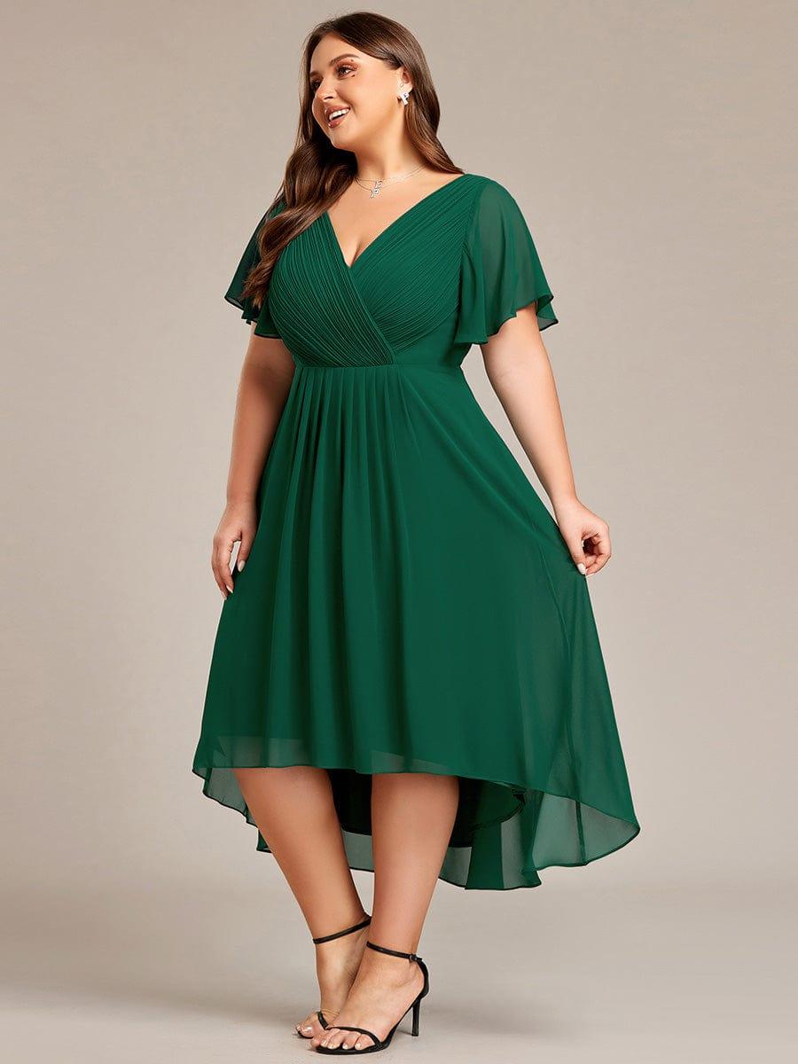 Curvy-Model im dunkelgrünen Kleid, seitlich lächelnd, Hand am Rock, Vokuhila-Saum aus Chiffon gut erkennbar. 39