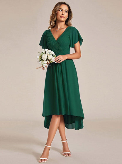 Dunkelgrünes Kleid, getragen mit einem Strauß weißer Blumen und weißen Sandaletten, Blick seitlich nach oben. 13