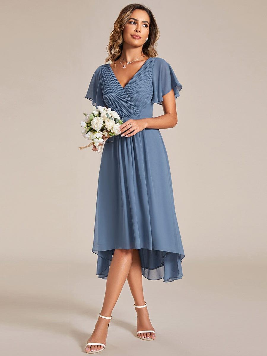 Taubenblaues Kleid getragen mit einem Strauß weißer Blumen in der Hand, Blick zur Seite, asymmetrischer Chiffonsaum. 8