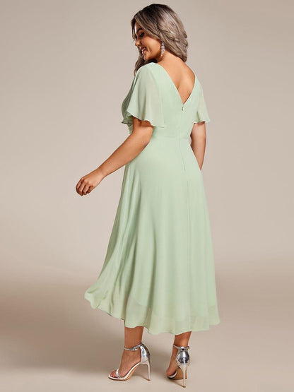 Rückansicht des mintgrünen Chiffonkleids mit tiefem V-Rückenausschnitt, Reißverschluss und vorne kürzerem, hinten längerem Saum an einem Plus-Size-Model. 82