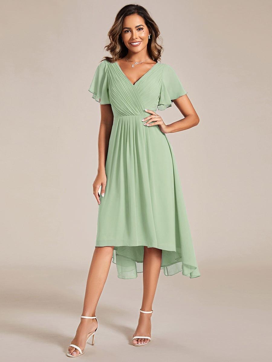 Salbeigrünes Chiffonkleid mit V-Ausschnitt, Flatterärmeln und hoch-tiefem Saum von vorn, Model mit Hand in der Hüfte. 76