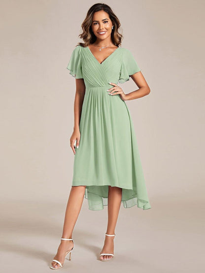 Salbeigrünes Chiffonkleid mit V-Ausschnitt, Flatterärmeln und hoch-tiefem Saum von vorn, Model mit Hand in der Hüfte. 76