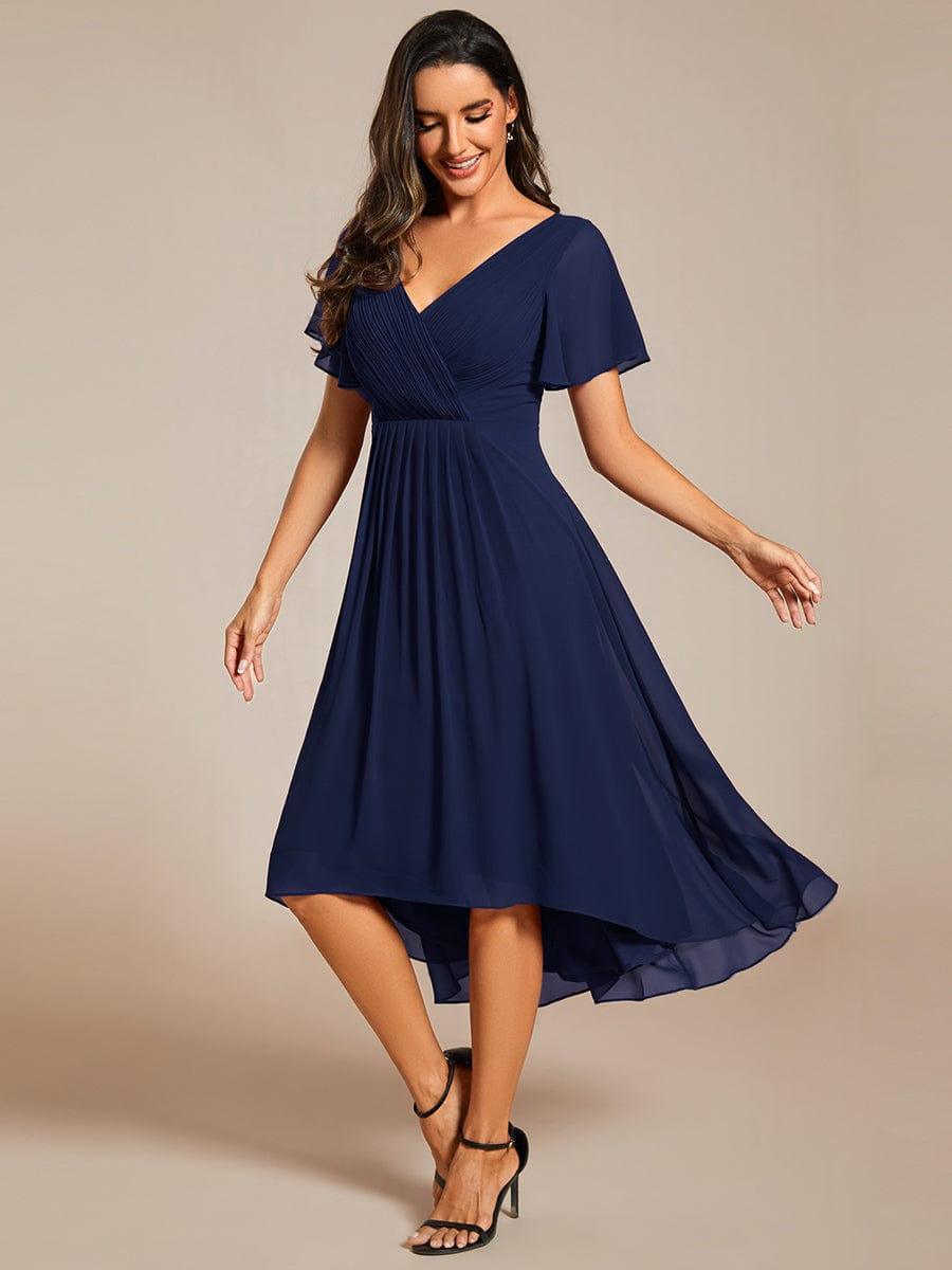 Marineblaues Chiffonkleid, Model schwingt den Rock und lächelt, der Vokuhila-Saum ist in Bewegung zu sehen. 52
