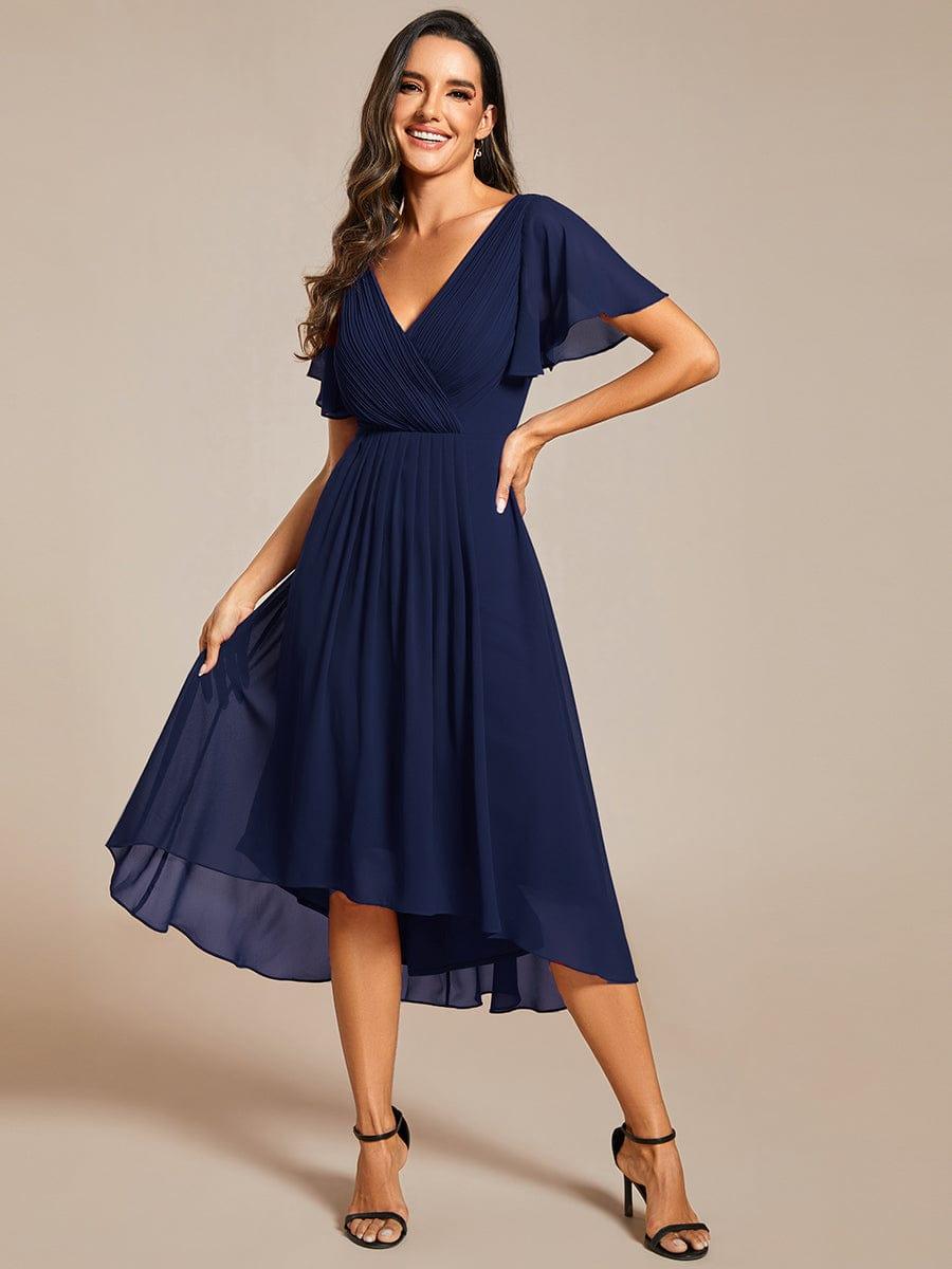 Marineblaues Kleid frontal, Model hält den Rock mit einer Hand seitlich hoch, schwarze Riemchensandaletten. 54