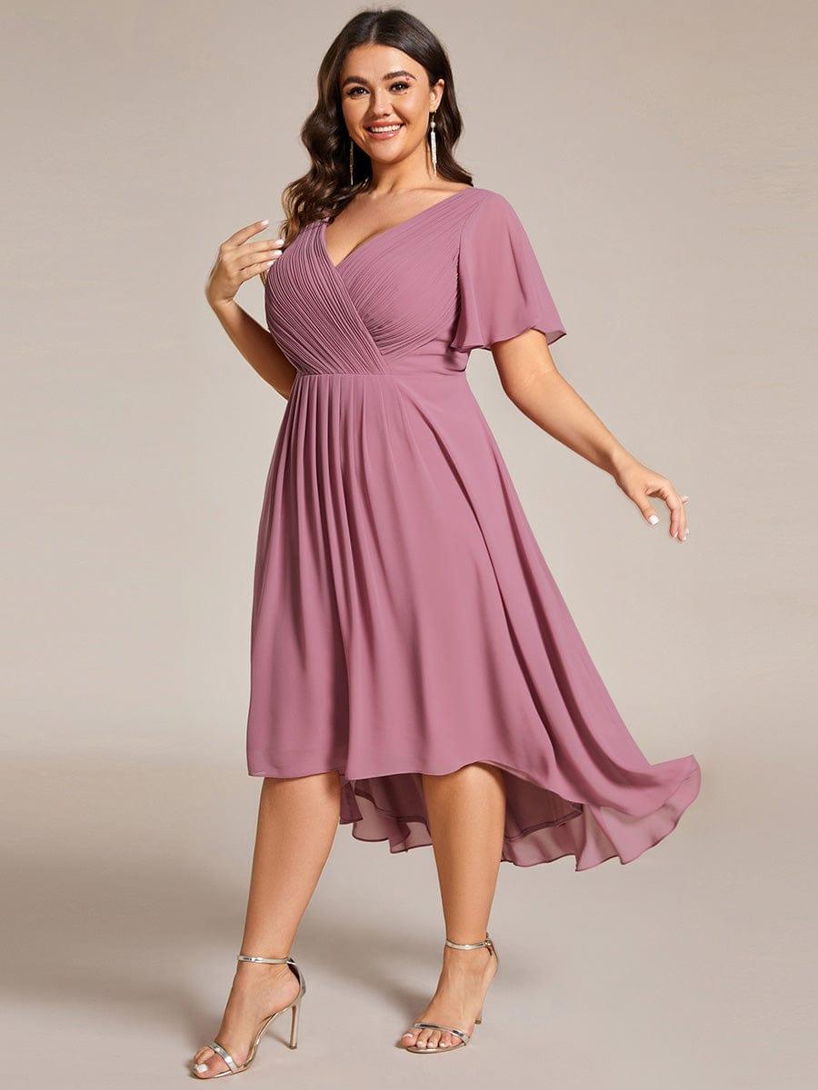 Plus-Size-Model in leichter Drehung im mauvefarbenen Kleid, der asymmetrische Chiffonsaum schwingt dabei sichtbar mit. 67
