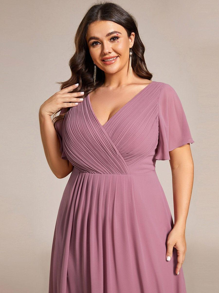 Oberteil-Detail des mauvefarbenen Kleids an einem Plus-Size-Model: gerafftes Wickeldekolleté und weich fallende Flatterärmel. 65