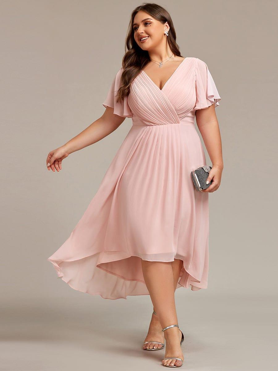 Curvy-Model im rosafarbenen Chiffonkleid mit V-Ausschnitt und Flatterärmeln, Clutch in der Hand, silberne Sandalen. 31