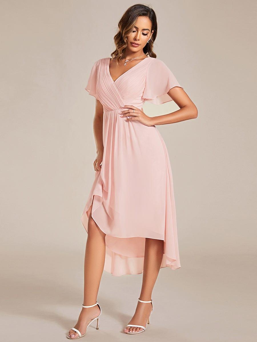 Rosé Kleid in Bewegung: Model hebt den Rocksaum leicht an und zeigt die fließende, asymmetrische Chiffonlänge. 19