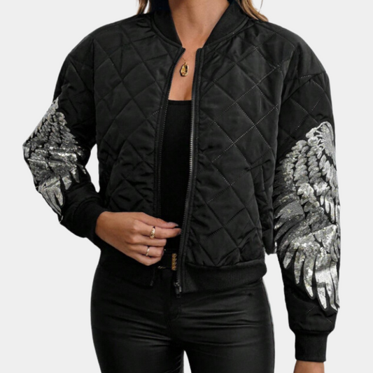 Frau trägt schwarze Bomberjacke mit silbernen Flügel-Designs, gesteppter Stoff, modisch.