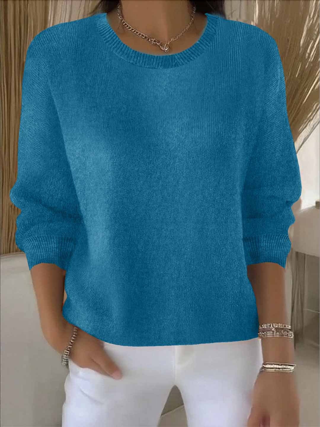 Frontansicht des petrolblauen Strickpullovers, vom Model zu weißer Hose und Halskette getragen 12