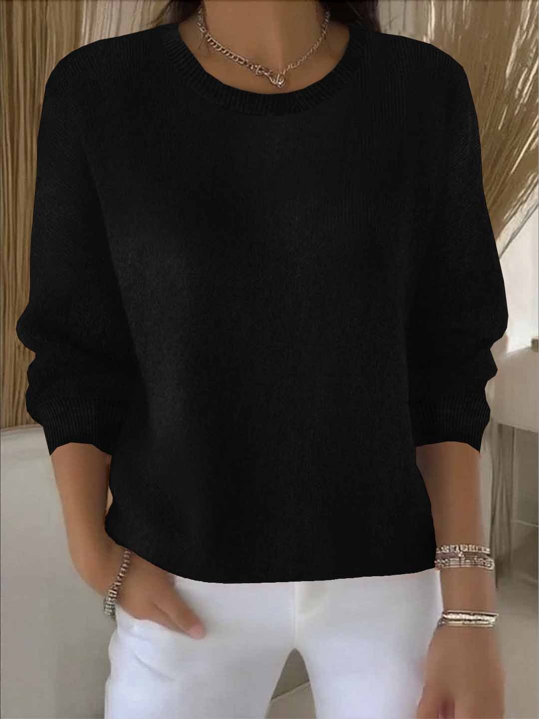 Frontansicht des schwarzen Strickpullovers mit Rundhalsausschnitt, getragen zu weißer Hose und Silberschmuck 7