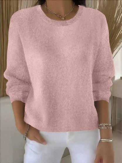 Frontansicht des rosafarbenen Strickpullovers, von einem Model zu weißer Hose und Halskette getragen 2