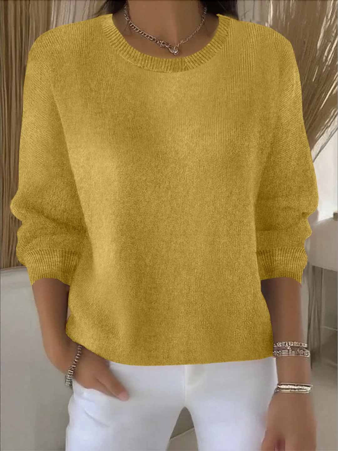 Frontansicht des senfgelben Strickpullovers, vom Model zu weißer Hose und Halskette getragen 8