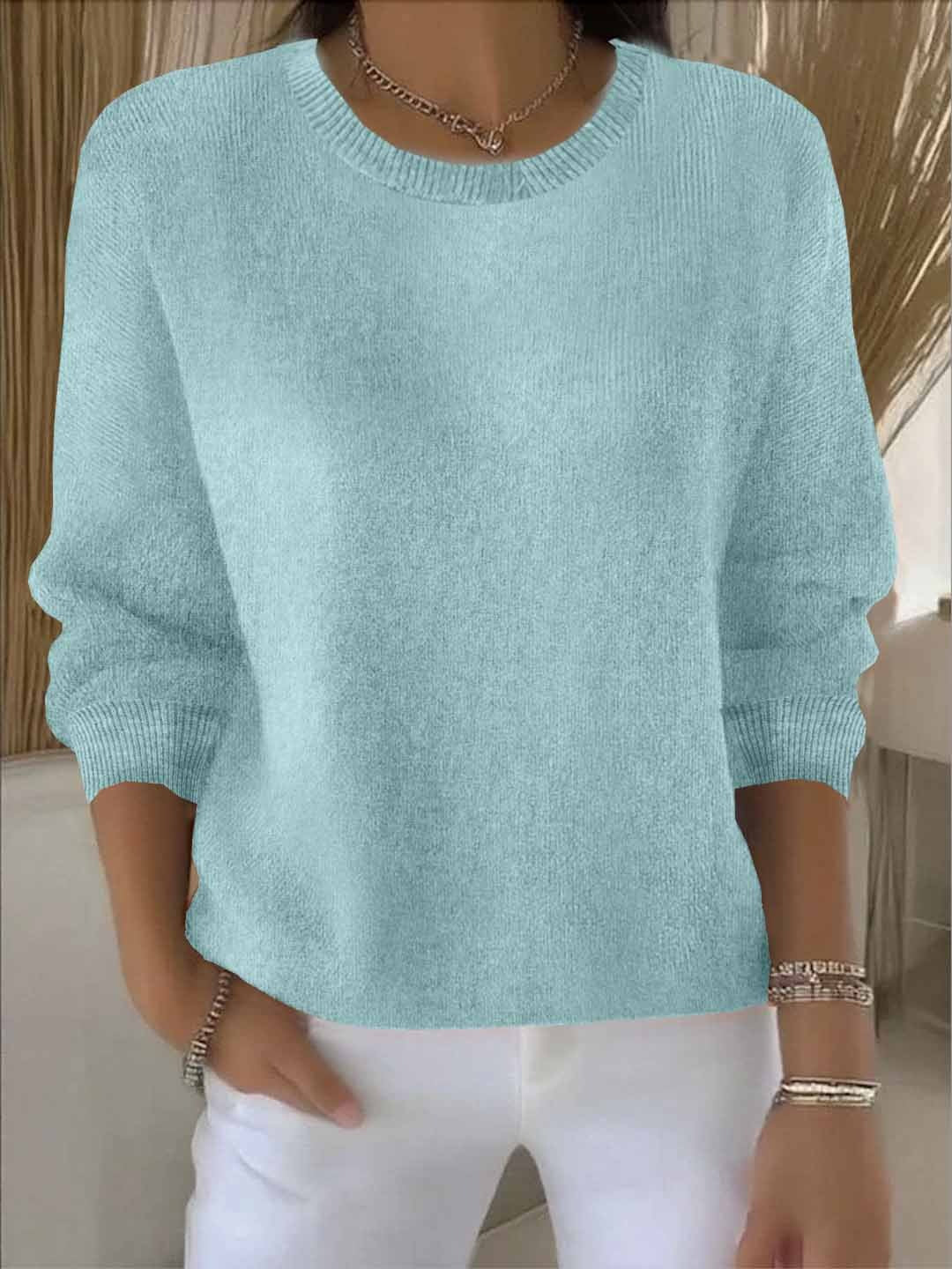 Frontansicht des hellblau-türkisen Strickpullovers, vom Model zu weißer Hose und Armbändern getragen 10