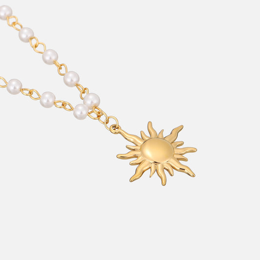 Schräge Nahaufnahme des goldenen Sonnenanhängers mit glänzender Mitte und der angrenzenden Perlenkette mit goldenen Verbindungsgliedern. 2