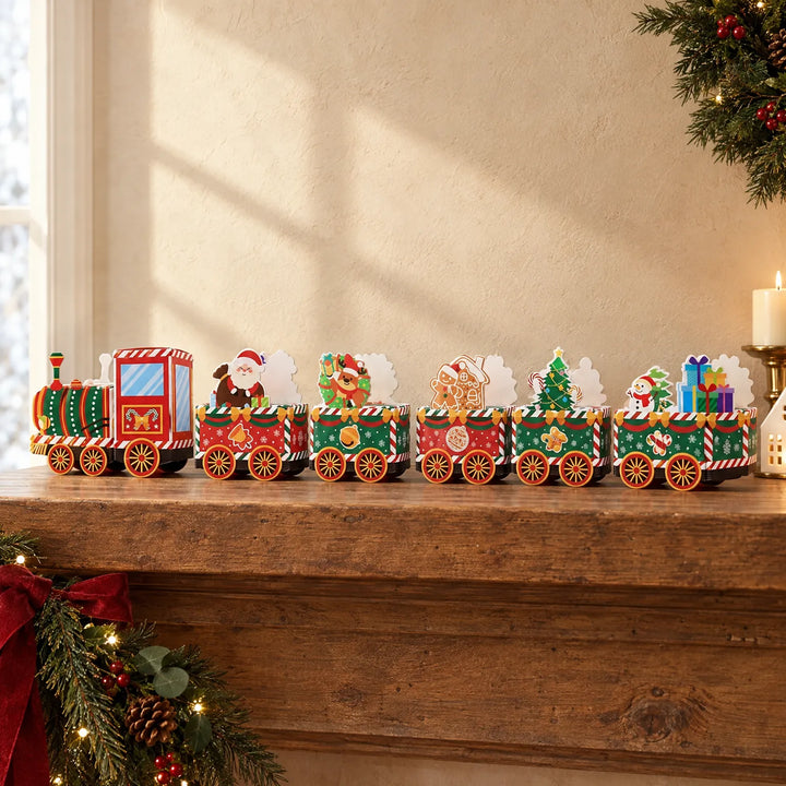 Der aufgebaute Papierzug mit Lok und fünf Waggons steht auf einem Holzsims, umgeben von Tannenzweigen, Kerze und weihnachtlicher Dekoration. 1