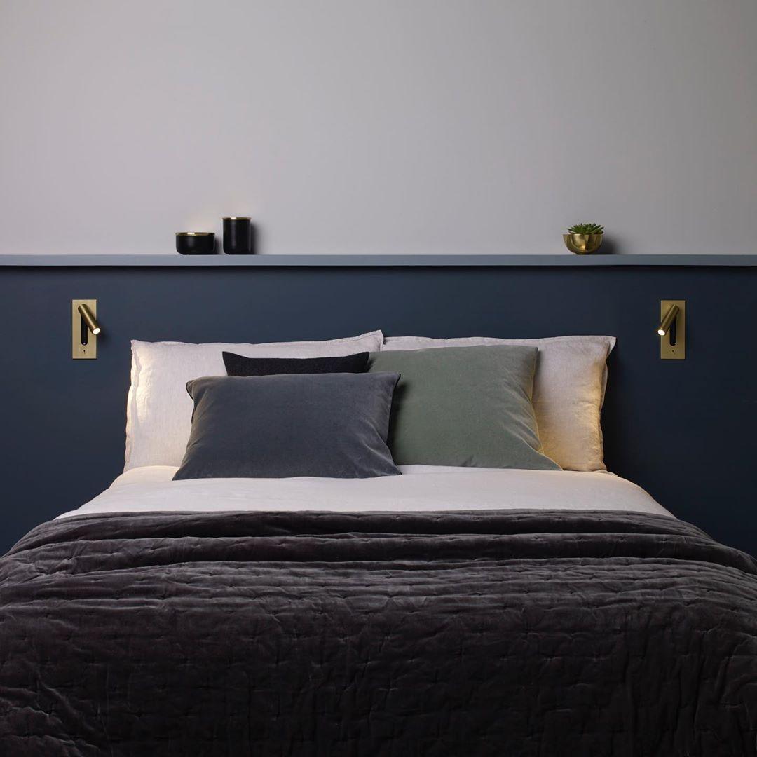 Zwei goldfarbene Leseleuchten links und rechts über einem Bett vor dunkelblauer Wand mit Regalbrett 35