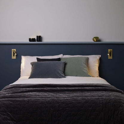 Zwei goldfarbene Leseleuchten links und rechts über einem Bett vor dunkelblauer Wand mit Regalbrett 35