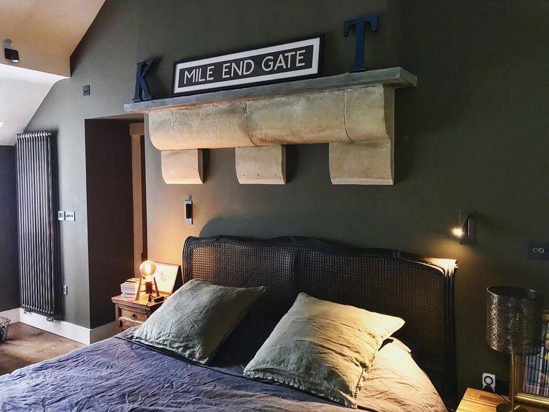Schlafzimmer mit dunkelgrüner Wand und Steinkonsole, zwei Wandleuchten zu beiden Seiten des Betts mit Korbgeflecht-Kopfteil 37