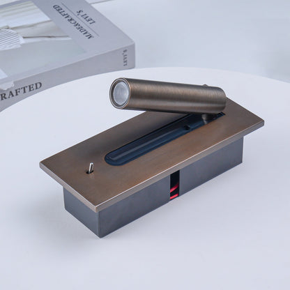 Wandleuchte in Bronze liegend auf einem weißen Tisch, Rückgehäuse und Kabel sichtbar, daneben ein Buch 13