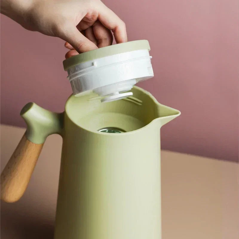 Grüne Thermoskanne mit Holzgriff, nordisches Design, abnehmbarer Deckel, stilvoll und funktional.