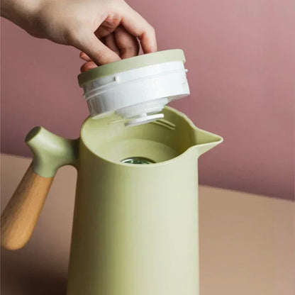 Grüne Thermoskanne mit Holzgriff, nordisches Design, abnehmbarer Deckel, stilvoll und funktional.