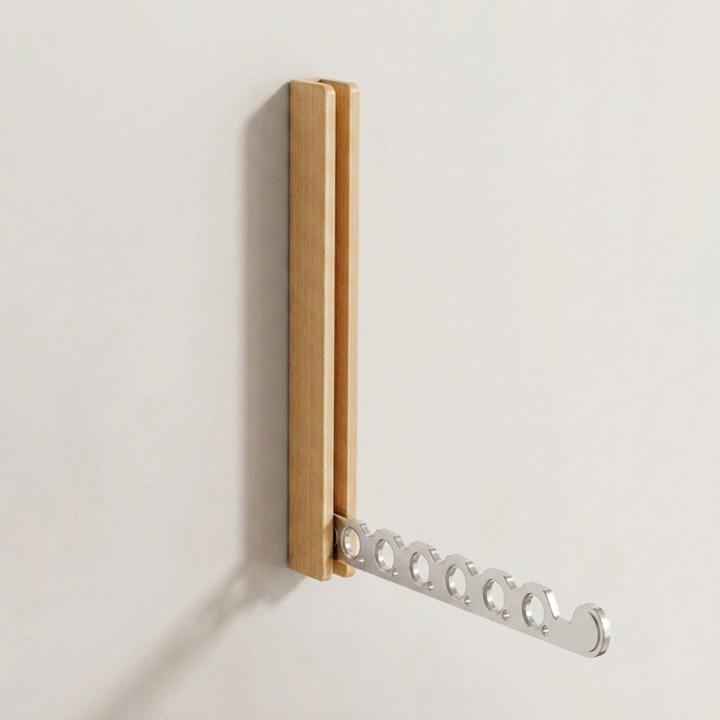 Helle Holzgarderobe mit ausgeklapptem silbernem Metallarm mit sechs Löchern, leer, an einer weißen Wand. 9