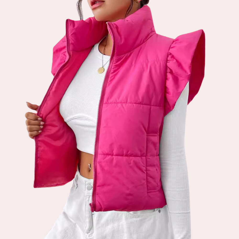 Frau in pinker Steppweste mit Rüschenärmeln, weißem Top und Hose, modisch, trendy.