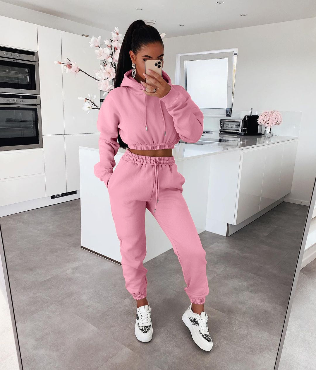 Frau in rosa Jogginganzug in moderner Küche, Freizeitmode, bequeme Kleidung, Sportbekleidung.