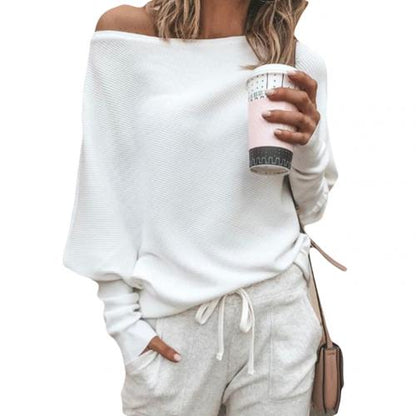 Frau in weißem Pullover und Jogginghose hält Kaffeebecher, lässige Mode, Freizeitkleidung.
