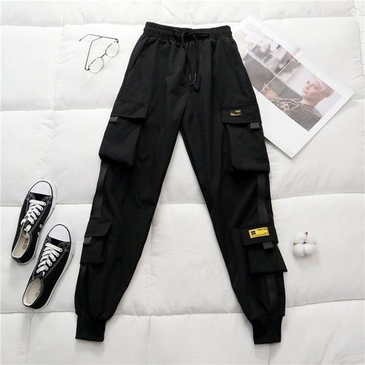 Schwarze Cargohose mit Taschen, Kordelzug, Baumwolle, lässig, Herrenmode, auf Bett.