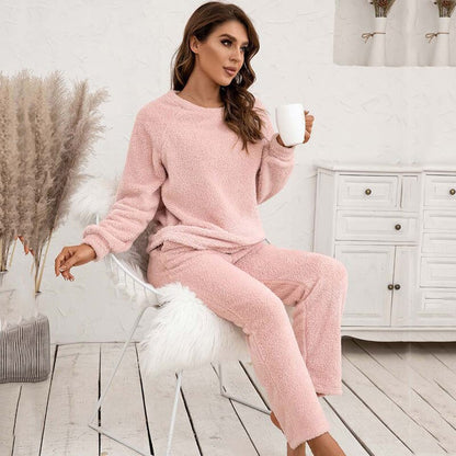 Frau in rosa Fleece-Pyjama mit Tasse, sitzt auf Stuhl, gemütliche Winterkleidung.