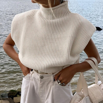 Frau in cremefarbenem Strickpullover am Wasser, modisch, ärmellos, Rollkragen, Herbstmode.