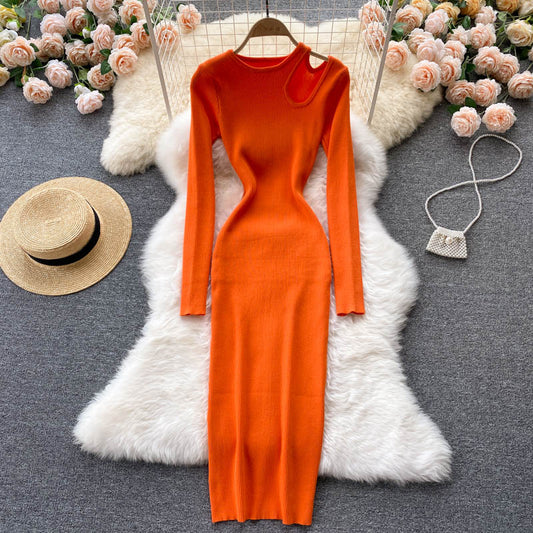 Orange Strickkleid mit Cut-Out, langärmelig, figurbetont, auf weißem Fell, umgeben von Rosen.