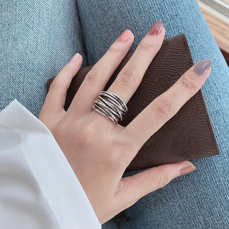 Silberner Stapelring an Hand, braune Geldbörse, blaue Jeans, modisches Accessoire.