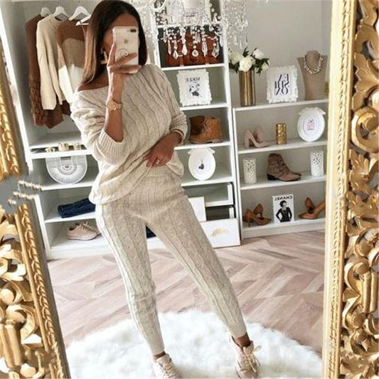 Frau in beigem Strickpullover und Hose, Spiegel-Selfie, modisches Outfit, gemütliches Wohnzimmer.