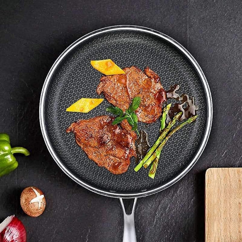 Bratpfanne mit Steak, Spargel und Kartoffeln auf schwarzem Hintergrund, Edelstahl, Antihaftbeschichtung.