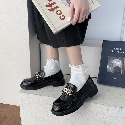 Schwarze Lackleder-Loafer mit goldener Kette, Damenmode, eleganter Schuh, stilvoller Look.