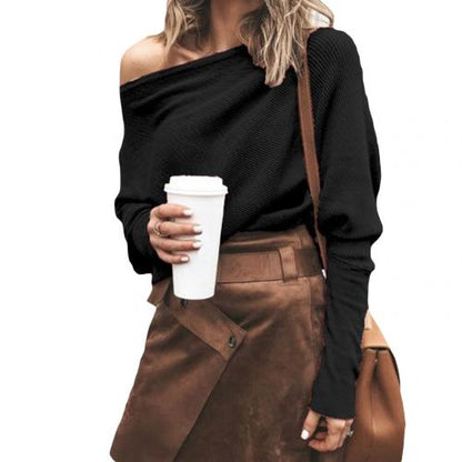 Frau in schwarzem Pullover und braunem Rock mit Kaffeebecher und Umhängetasche.