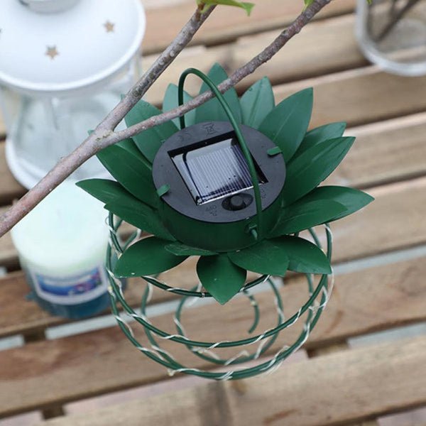 Grüne Solarlampe in Ananasform, hängend, auf Holztisch, Gartenbeleuchtung.