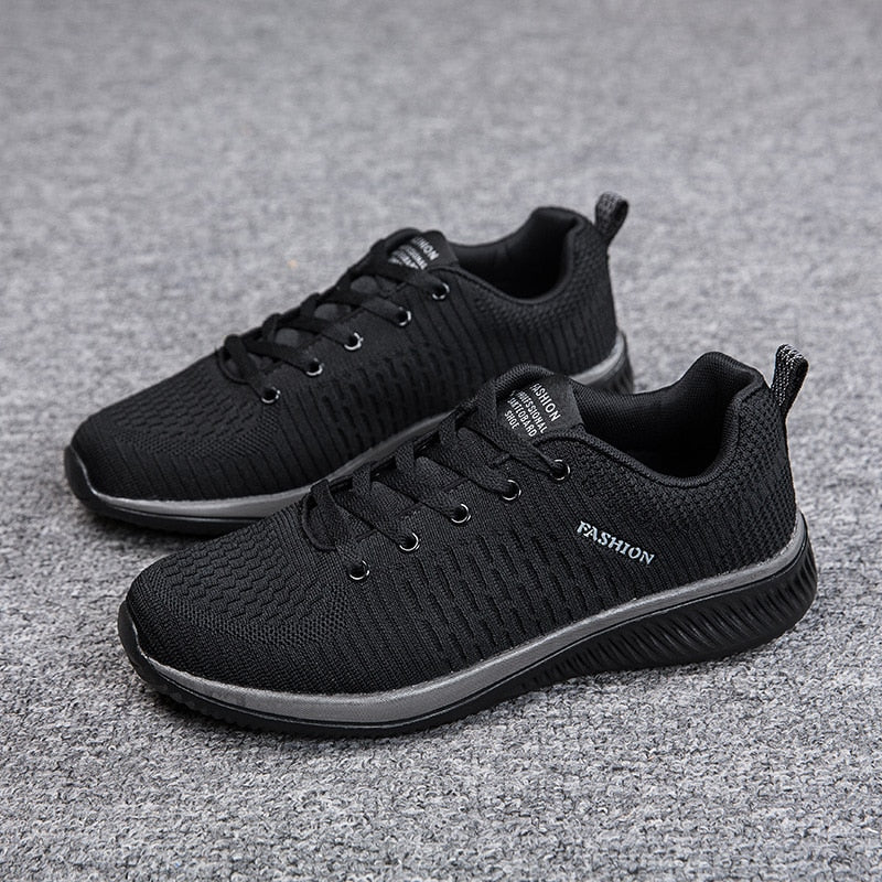 Schwarze Herren-Sneaker, atmungsaktiv, rutschfest, modisch, auf grauem Teppich.