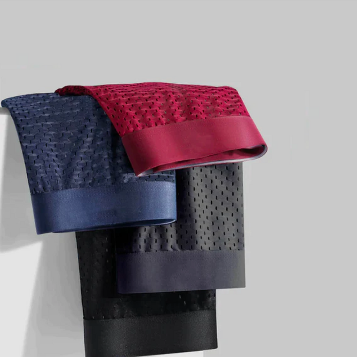 Vier gefaltete Boxershorts in Blau, Rot, Grau und Schwarz hängen übereinander an einer Kante 3