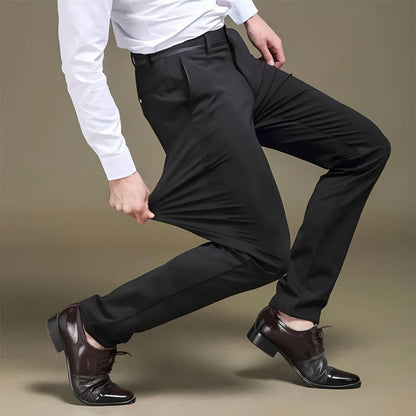 Mann in schwarzer Stretchhose, weißem Hemd, braunen Lederschuhen, zeigt Flexibilität der Hose.